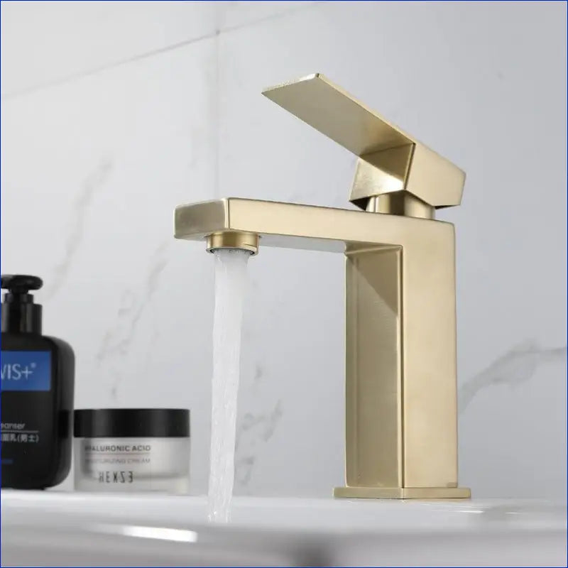 Modern gold-colored bathroom faucet with a square design.