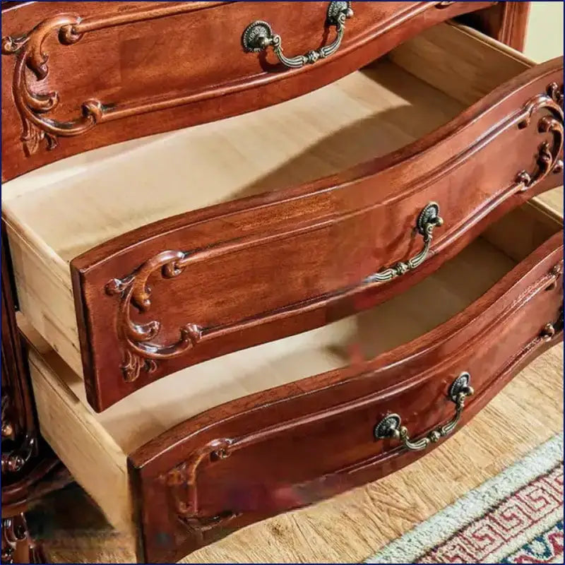 Ornate wooden dresser drawers with decorative curved fronts and metal handles.