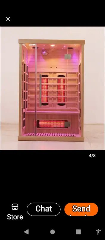 Wooden infrared sauna cabin illuminated with pink LED lighting.