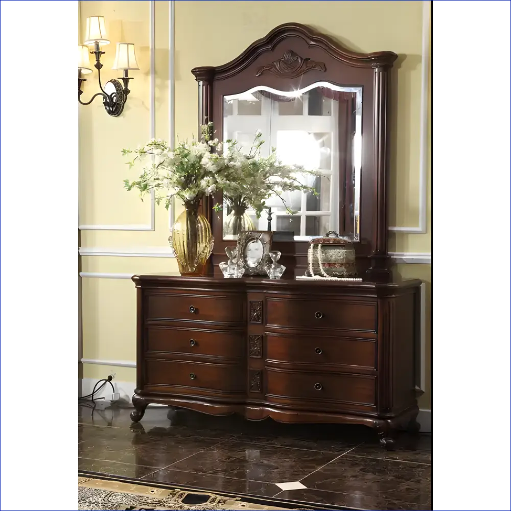 Dark wooden dresser with an ornate mirror and decorative floral arrangement on top.