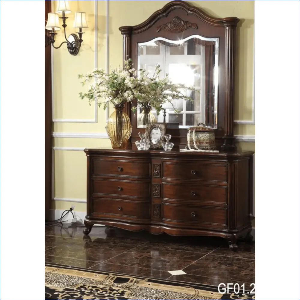 Dark wooden dresser with an ornate mirror and decorative floral arrangement on top.