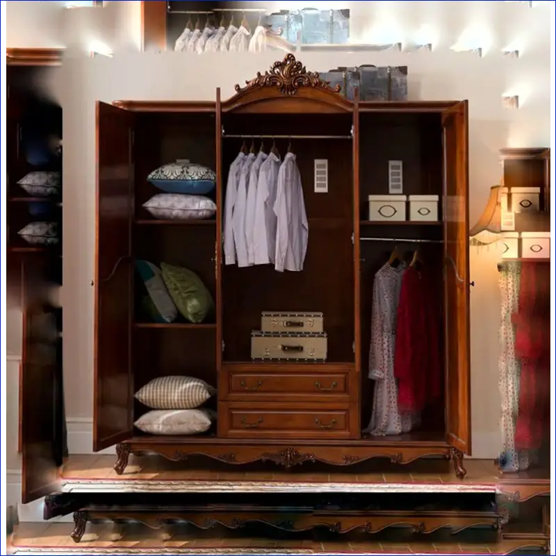 Ornate wooden wardrobe with carved crown detailing and three compartments displaying clothing and storage boxes.