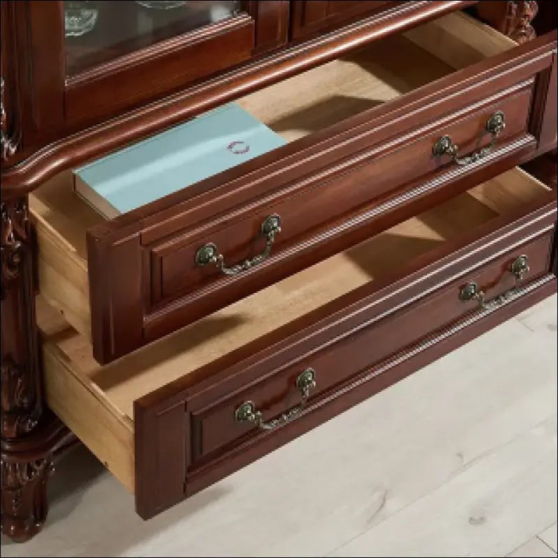 Wooden dresser drawers with ornate brass handles pulled open.